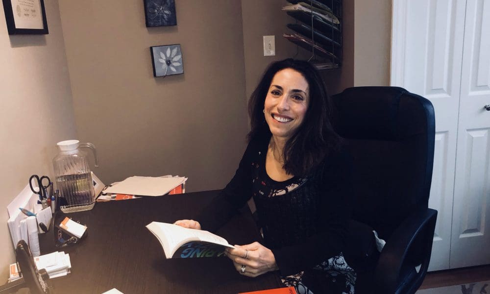 Lynn R Zakeri in her personal office holding a book